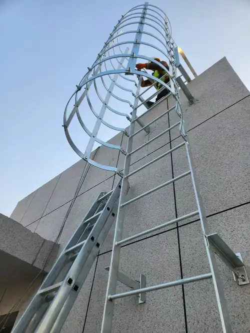 Escalera con jaula anticaídas amarilla instalada